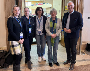 Auf dem Bild sind 5 Personen zu sehen, die nebeneinander stehen. Sie stehen vor einer offenen Tür im Bayerischen Landtag.