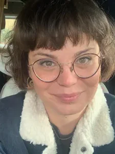 Ein Selfie von einer jungen Frau mit Brille, die in die Kamera lächelt.