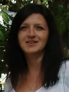 Eine Nahaufnahme von einer schwarzhaarigen Frau mittleren Alters.