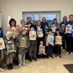 Mehrere Erwachsene und Kinder stehen glücklich mit Schokoadventskalendern beisammen.