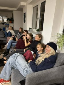 Kinder und Mitarbeitende sitzen auf einem Sofa und lauschen dem Pelzmärtel.