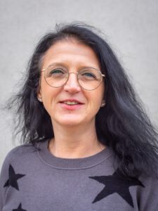 Ein Portrait einer schwarzhaarigen Frau mittleren Alters.