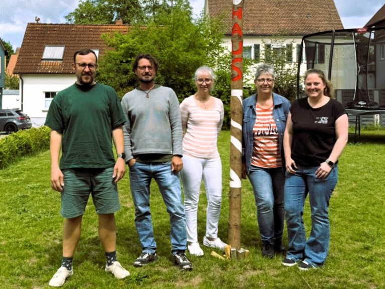 Fünf Erwachsene stehen auf einer Wiese