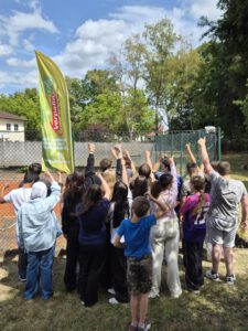 Kinder und Erwachsene von hinten, die die Arme hochstrecken, sowie die Verpa Fahne
