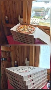 Ein Stapel Pizza Kartons und ein offener Karton mit einer Pizza